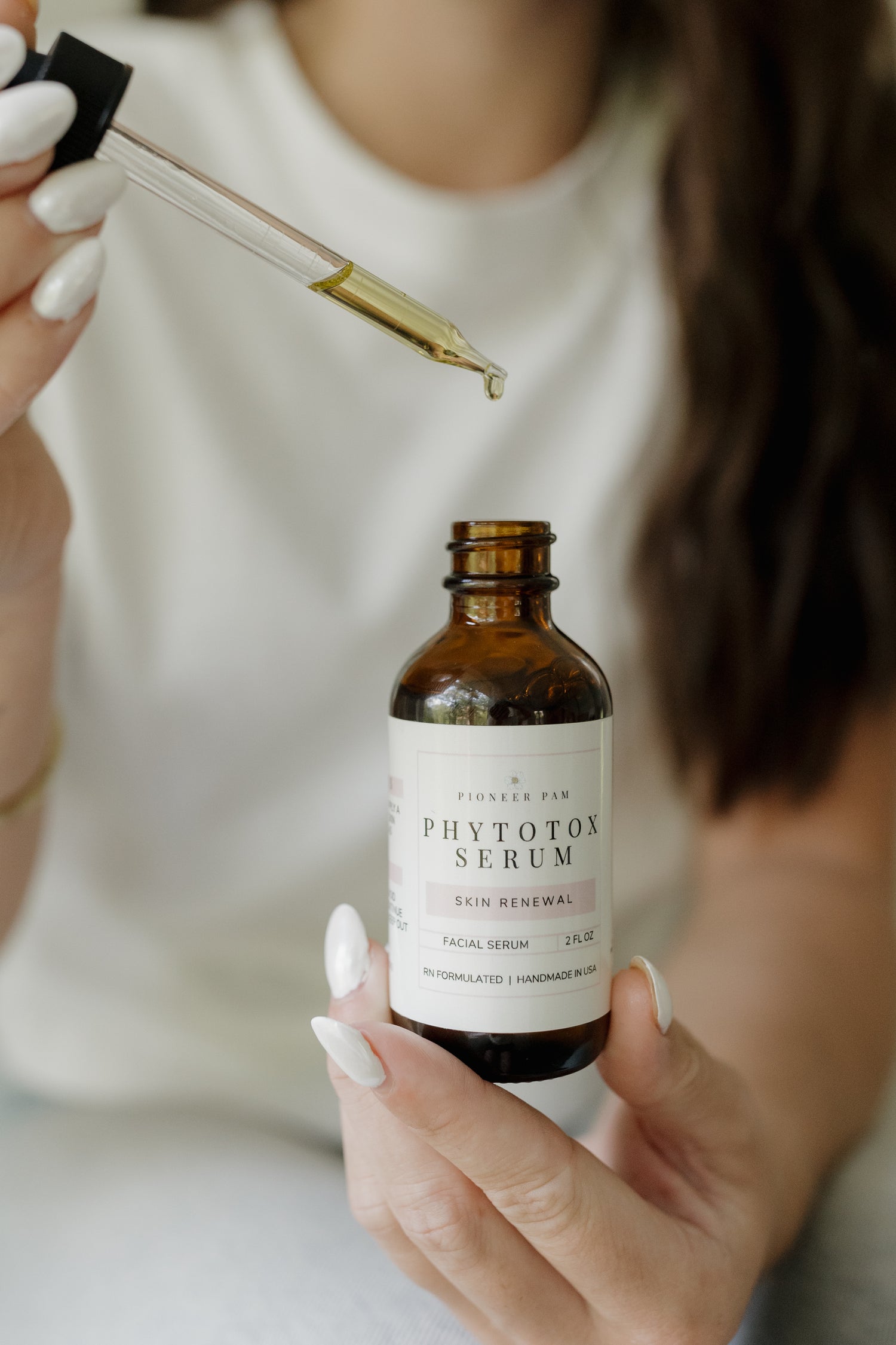 Woman holding a dropper of Phytotox Serum above the bottle
