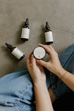 Woman holding Phytotox Tallow with Mane Magic and Phytotox Serum bottles laid out nearby