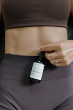 Woman in athletic wear holding a dropper of Pioneer Pam Liver Detox Tincture near her stomach