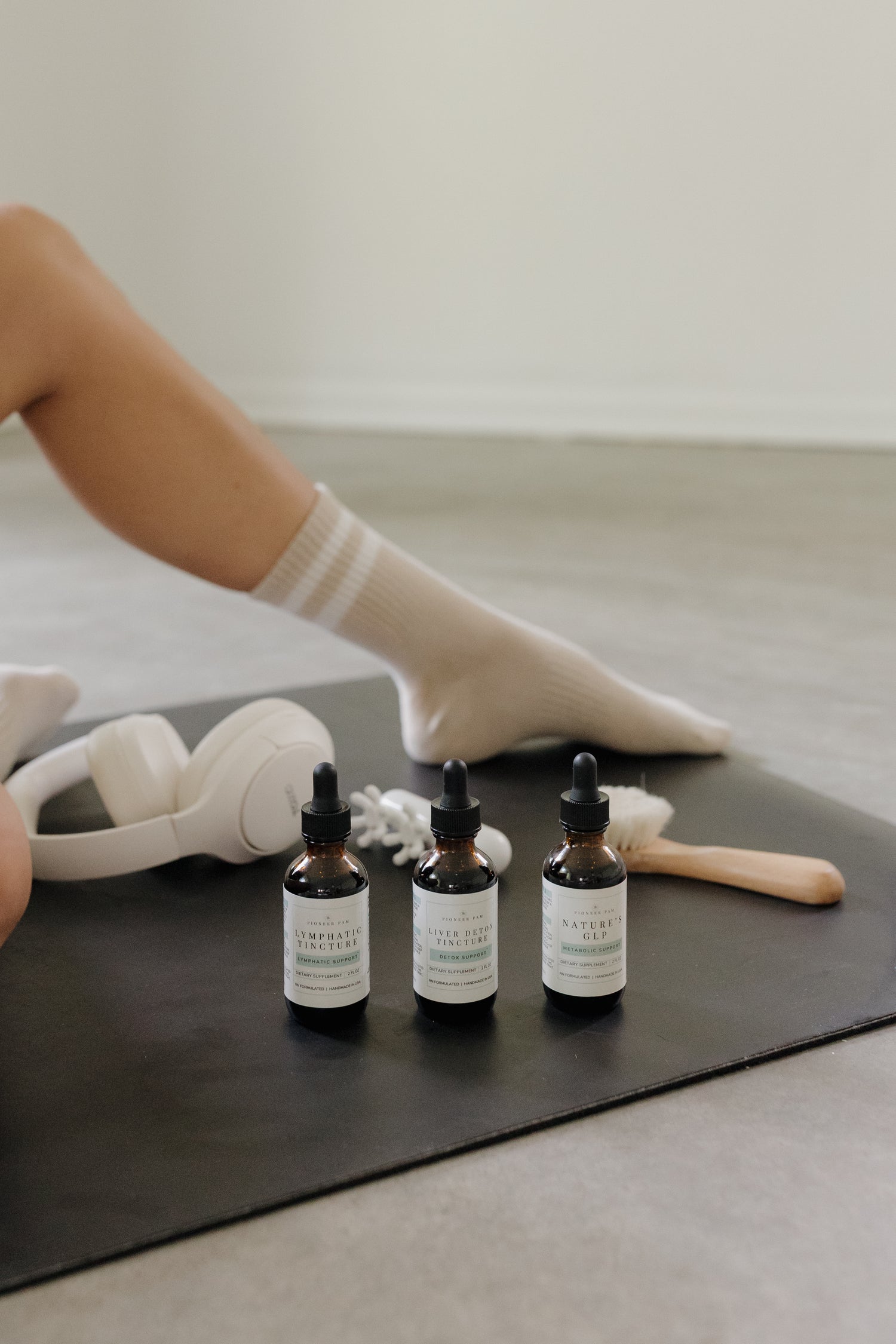 Woman in athletic wear holding a Pioneer Pam tincture bottle near her stomach