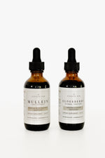 Two amber glass dropper bottles of Pioneer Pam Mullein Leaf Extract and Elderberry Herbal Tincture on a white background.